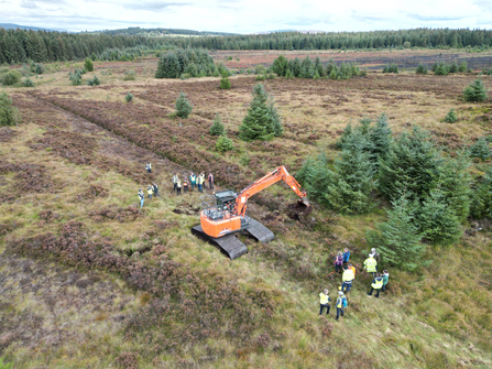 Contractors and restoration practitioners observing machinery demonstration showcasing peatland restoration techniques